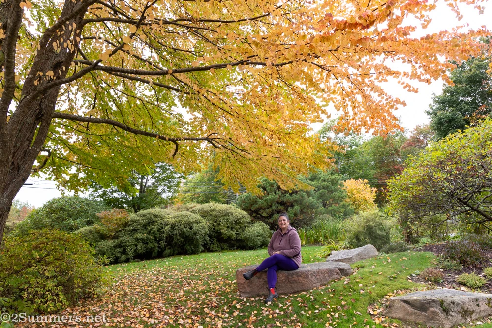 Susanna sitting on a rock under a tree in the garden